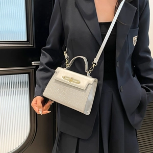 Silver glitter crossbody bag with gold turn-lock worn by model in professional attire