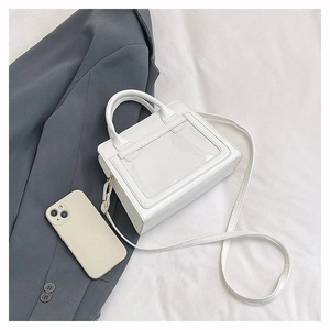 Détail d'un sac bandoulière blanc en similicuir avec fenêtre PVC sur fond de tissu blanc