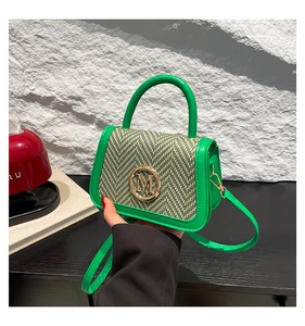 Detail of green woven texture and golden M logo on a luxury mini top-handle bag
