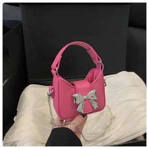 Gros plan du mini sac à main rose avec un gros nœud métallique argenté et chaîne