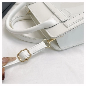 Détails du sac à main blanc montrant le cuir texturé, la boucle dorée et la bandoulière