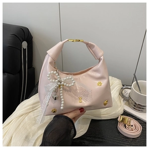 Close-up of sakura pink handbag with pearl lace bow and golden cat paw relief