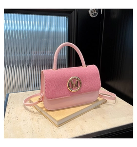 Détail du sac rose avec rabat en tissu rayé et fermoir métallique doré en M