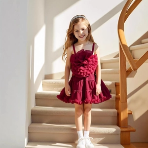 Detailed close-up of dark red girl's tutu dress with 3D floral accent and layered ruffles