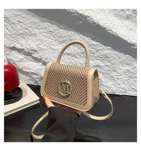 Close-up of beige woven texture handbag with metallic M logo and leather handle
