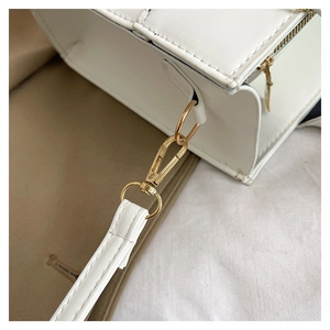 Detail of golden metal hook and detachable strap on white textured leather handbag