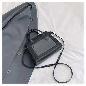 Détail d'un sac à main noir en cuir avec panneau en PVC transparent et poignée élégante