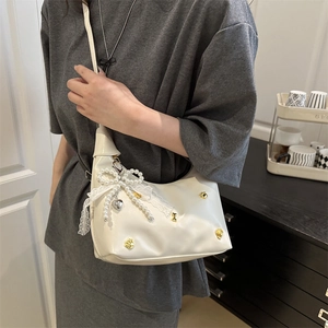 White dumpling bag with pearl bow and lace trim worn by model in home setting