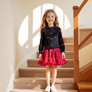Detail der dunkelblauen Strickjacke mit roten Schleifen und rotem Tutu-Rock für Mädchen