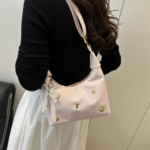 Pink faux leather shoulder bag with gold bone charms and a pearl lace bow detail