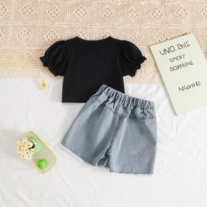 Détail de l'ensemble haut noir à manches bouffantes et short en jean effiloché fille