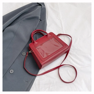 Vue détaillée d'un sac bandoulière en cuir rouge avec une fenêtre en PVC transparente