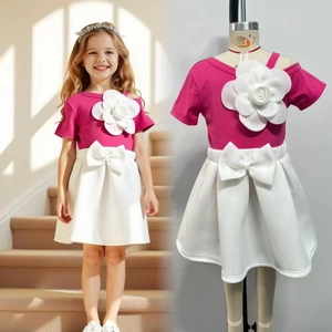 Detail view of pink girl's top with 3D flower and white skirt with a large bow
