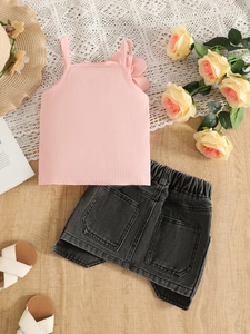 Détail d'un caraco rose pour fille avec fleur 3D et d'une jupe en jean foncé
