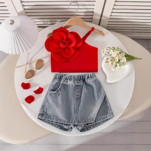 Flat lay of girl's summer set with red floral one-shoulder top and denim shorts