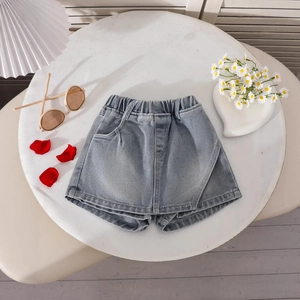 Detail of girls light blue denim skort with elastic high waist and asymmetric front