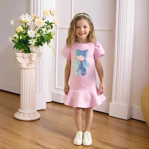 Close-up of pink girls dress with sequined blue bear embroidery and ruffle hem details