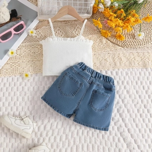 Detail von weißem Rüschen-Top und blauen Denim-Shorts mit sommerlicher Dekoration