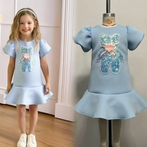 Detail of light blue girls' dress featuring sequined bear patch and pink bow decoration