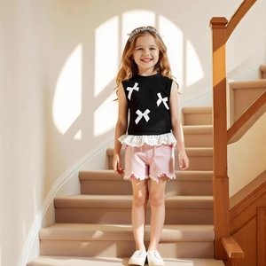 Detail of girls summer set featuring a bow lace vest and frayed pink denim shorts