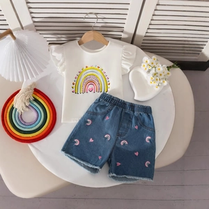 Detail of girls white cotton t-shirt with rainbow print and frayed denim shorts