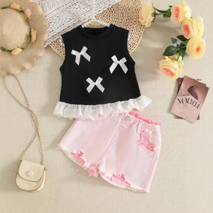 Detail of girls' black lace vest with white bows and pink distressed denim shorts set