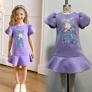 Detail of girls' purple party dress featuring sequined bear patch and ruffled hem