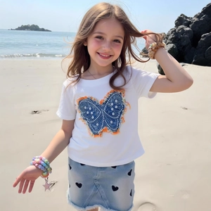 Détail du t-shirt blanc papillon et jupe en jean avec imprimés cœurs pour filles