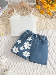 Mädchen Sommer-Set mit weißem Rüschen-Top und floralen Denim-Shorts auf einem Kleiderbügel