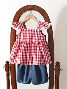 Ensemble d'été fille avec haut à carreaux rouges et short en jean sur cintre