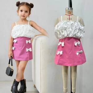 Details von weißem Rüschen-Oberteil und rosa Minirock mit Schleife für Mädchen