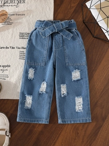 Girls' light blue ripped jeans with elastic waist and bow tie on dark wood background