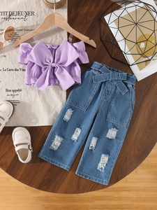 Girls lilac off-shoulder bow top and distressed denim jeans set on wooden table
