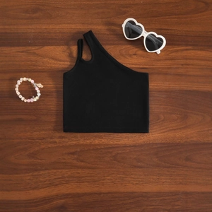 Détail d'un haut court en maille noire à une épaule avec découpe stylée sur la bretelle