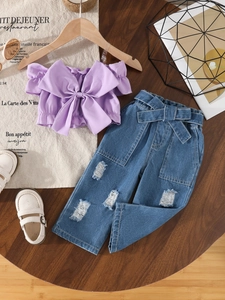 Girls lilac off-shoulder top with bow and distressed denim jeans set on wooden table
