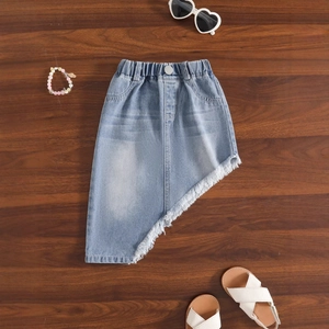 Détail de jupe en jean bleu clair avec ourlet asymétrique à franges et taille élastique