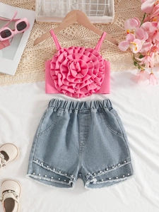 Ensemble été fille avec haut à fleur 3D et short en jean perlé sur un drap blanc