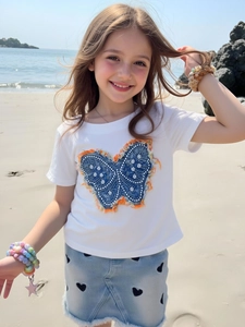 T-shirt blanc fille avec applique papillon et jupe en jean coeur sur la plage