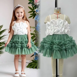 Detail of white top with 3D floral accent and green layered tulle skirt for girls