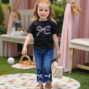 Close-up of girls' denim flare pants featuring stylish frayed hems and white bow details