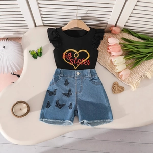Dettaglio set bambina: top nero con ruches e cuore dorato e pantaloncini in denim ricamati