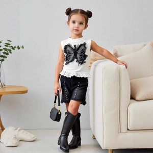 Details des weißen Mädchen-Tops mit schwarzem Netz-Schmetterling und Perlen-Jeansshorts