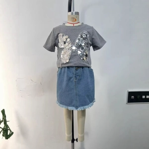 Détail du papillon en paillettes argentées sur t-shirt gris et ourlet en jean effilé