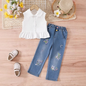Détail ensemble fille: haut blanc sans manches à volants et jean avec broderies fleurs
