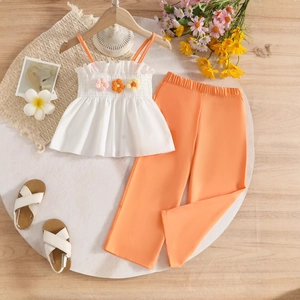 Flat lay of girl's white strap top with 3D floral accents and bright orange trousers