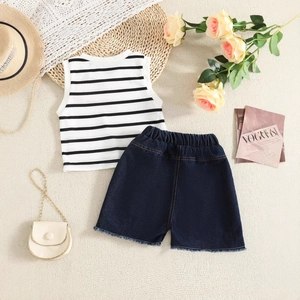 Flat lay of girl's striped tank top and denim shorts with fringe details and accessories