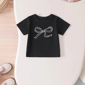 Close-up of black cotton girls T-shirt featuring a white bow print on a wooden background