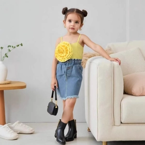 Détail du haut à fleurs jaune et de la jupe en jean bleu clair avec franges pour enfant