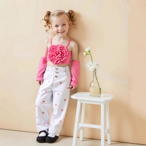 Détail d'un haut à fleurs roses et d'un pantalon blanc à cœurs sur un enfant