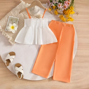 Detail of white textured camisole and orange wide-leg trousers for girls summer set